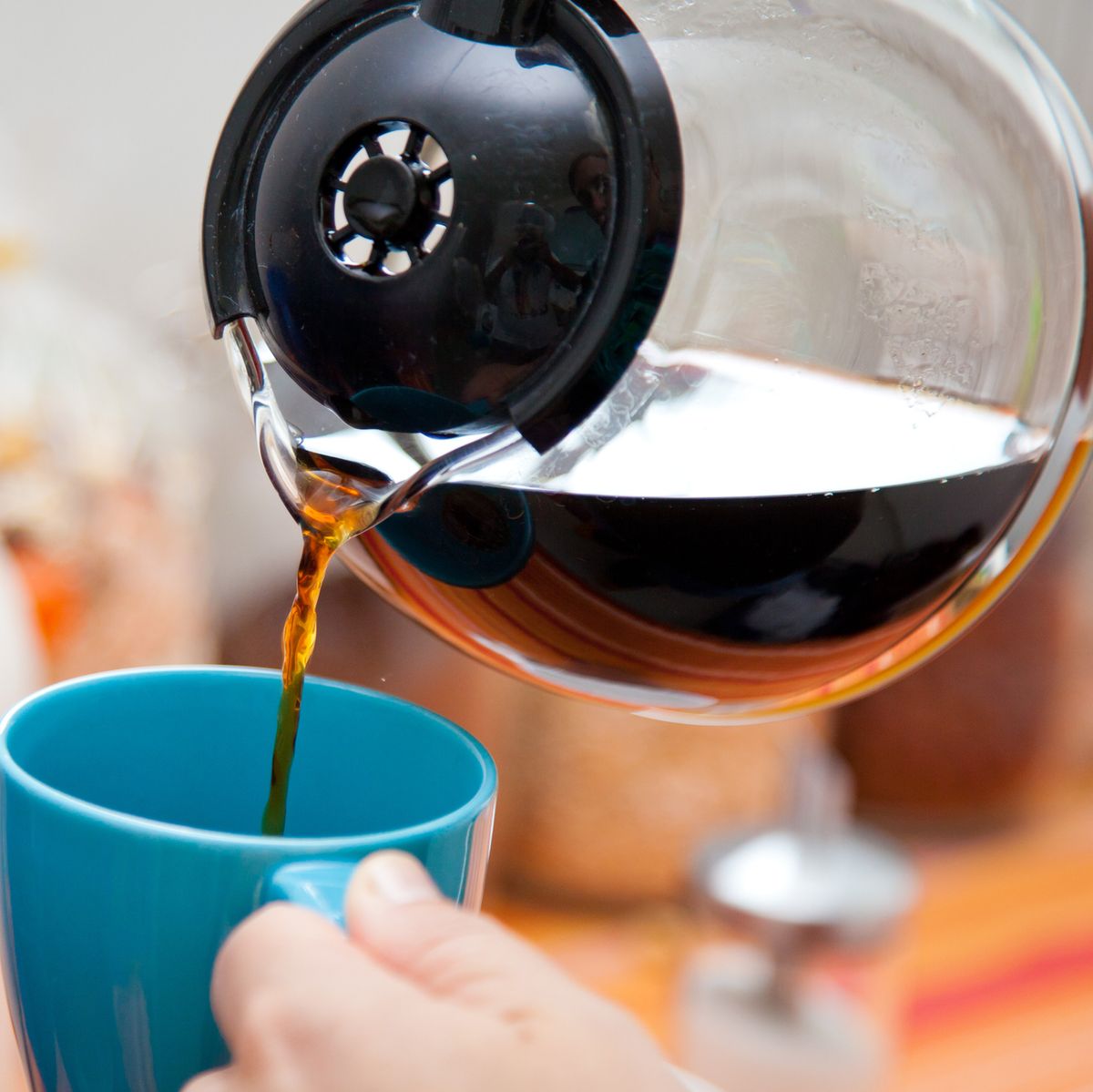 woman pouring coffee pot into a coffee mug in the kitchen