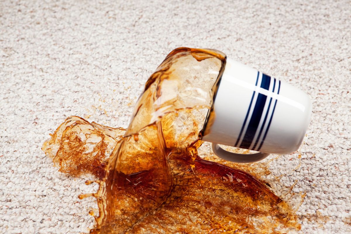 coffee spilling from cup onto carpet