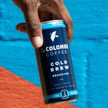 hand holding can of La Colombe cold brew coffee against a colorful wall