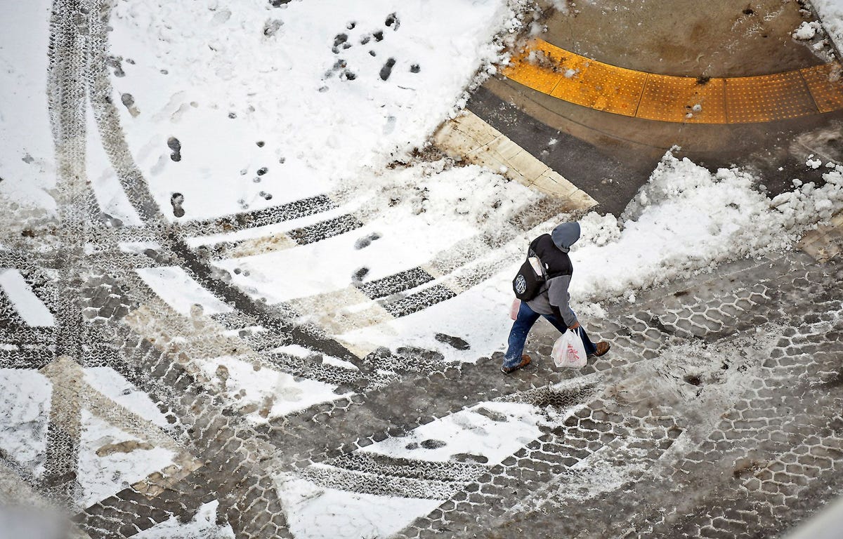 Een voetganger steekt op 20 januari de straat over in het centrum van Scranton in de Amerikaanse staat Pennsylvania nadat een winterstorm een groot deel van de VS met een laag sneeuw bedekte en enkele van de laagste temperaturen van het seizoen werden gemeten Het winterweer ontregelde het luchtverkeer en zorgde voor gladde wegen in de hele staat New England