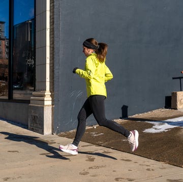 Runner in bright yellow jacket jogging past a building with large windows runner in bright yellow jacket jogging past a building with large windows