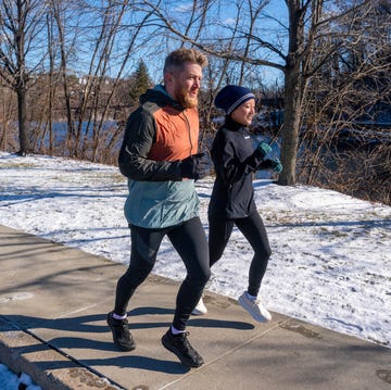 Two individuals jogging on a snowy path next to a river two individuals jogging on a snowy path next to a river