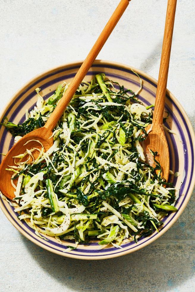 a bowl of green slaw with wooden utensils
