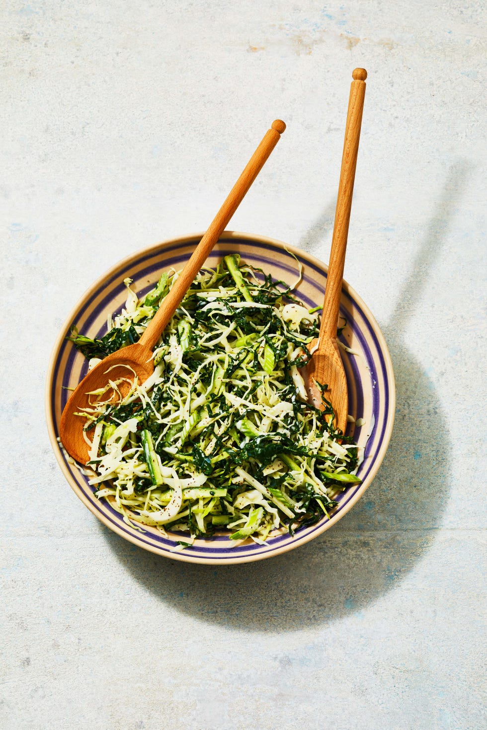 a bowl of green coleslaw with shredded cabbage, kale, jicama and cucumbers