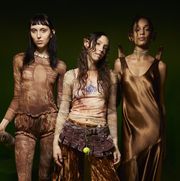 designer hillary taymour of collina strada, wearing brown tie dye and elf ears, stands backstage with two models at her fall 2023 show