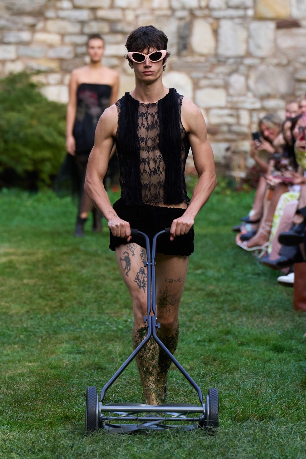 a model pushes an old fashioned lawnmower at collina strada