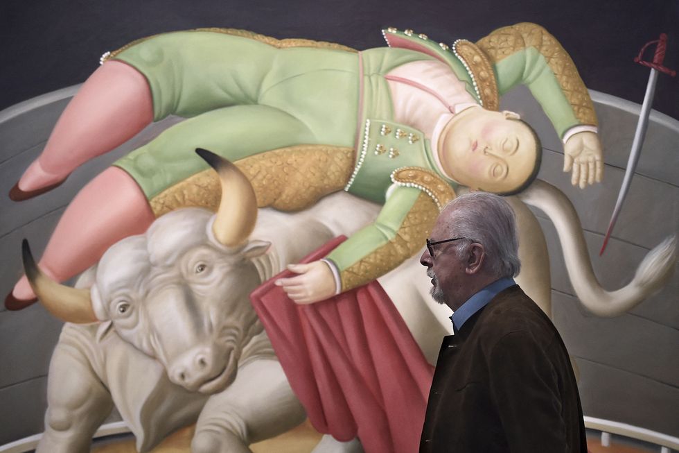 fernando botero standing in front of a painting depicting a bull and matador
