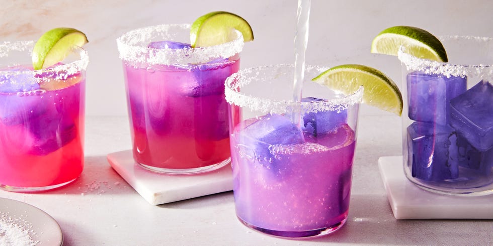 pink margarita with a purple ice cube with a salt rim and lime wedge