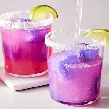 pink margarita with a purple ice cube with a salt rim and lime wedge
