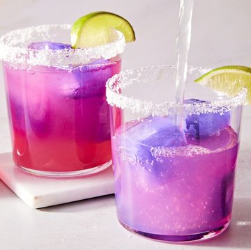 pink margarita with a purple ice cube with a salt rim and lime wedge