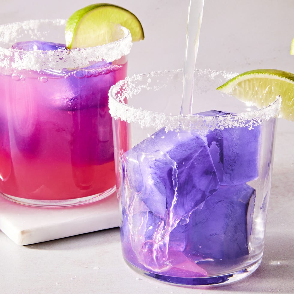 pink margarita with a purple ice cube with a salt rim and lime wedge