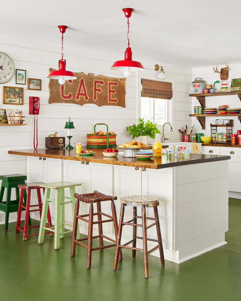 a white kitchen with green floors and colorful accessories