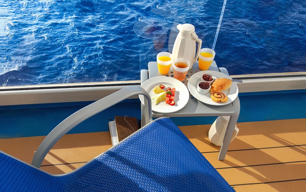 a colorful continental breakfast served on a balcony of a cruise ship at sea, with fruit, juice, breads and coffee