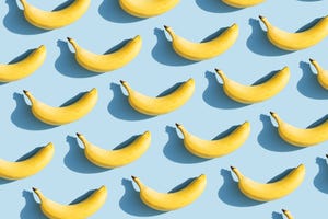 colorful fruit pattern of fresh yellow bananas on blue background with shadows fruit concept flat lay, top view