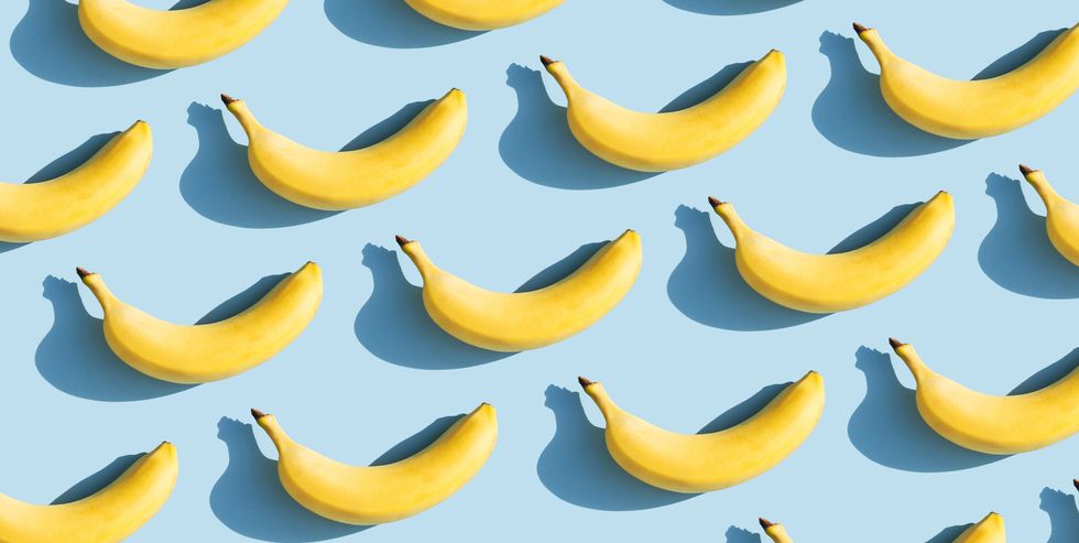 colorful fruit pattern of fresh yellow bananas on blue background with shadows fruit concept flat lay, top view