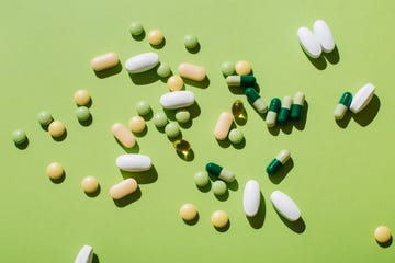 colorful pills and capsules on green background minimal medical concept flat lay, top view
