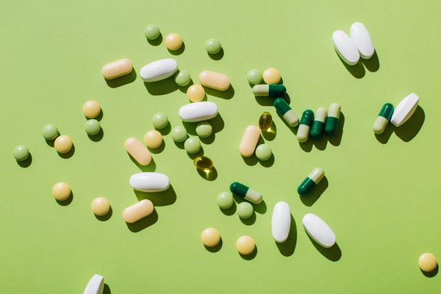 colorful pills and capsules on green background minimal medical concept flat lay, top view