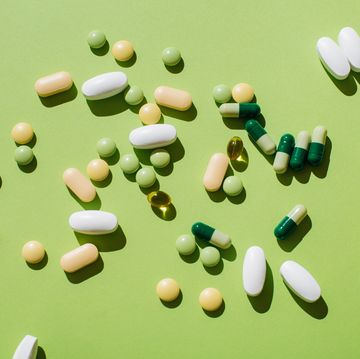 colorful pills and capsules on green background minimal medical concept flat lay, top view
