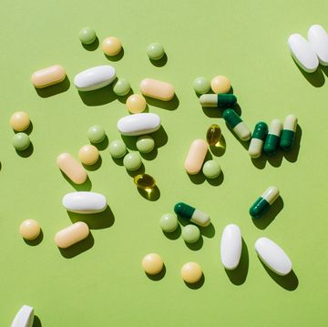 colorful pills and capsules on green background minimal medical concept flat lay, top view