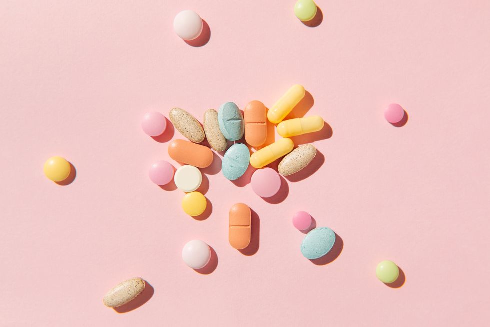 colorful pills and capsules on pink background taking tablets, vitamins, painkillers, medications and dietary supplements minimal medical, health care, pharmacology concept flat lay, top view