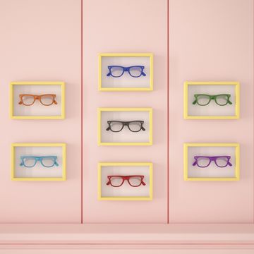 Colourful glasses in yellow frames hanging on pink wall