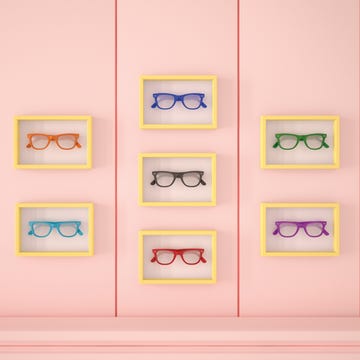 Colourful glasses in yellow frames hanging on pink wall