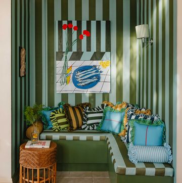 blue and green striped wallpaper in a room with a bench and cushions