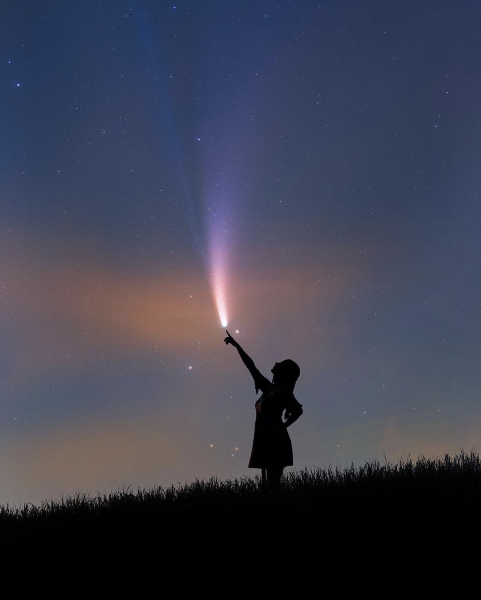 girl pointing to comet in sky