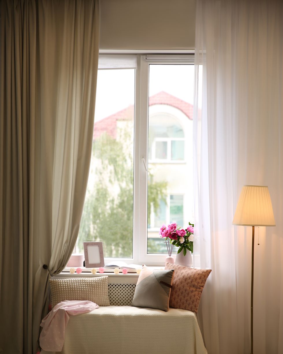comfortable place for rest with cushions and peony flowers near window indoors