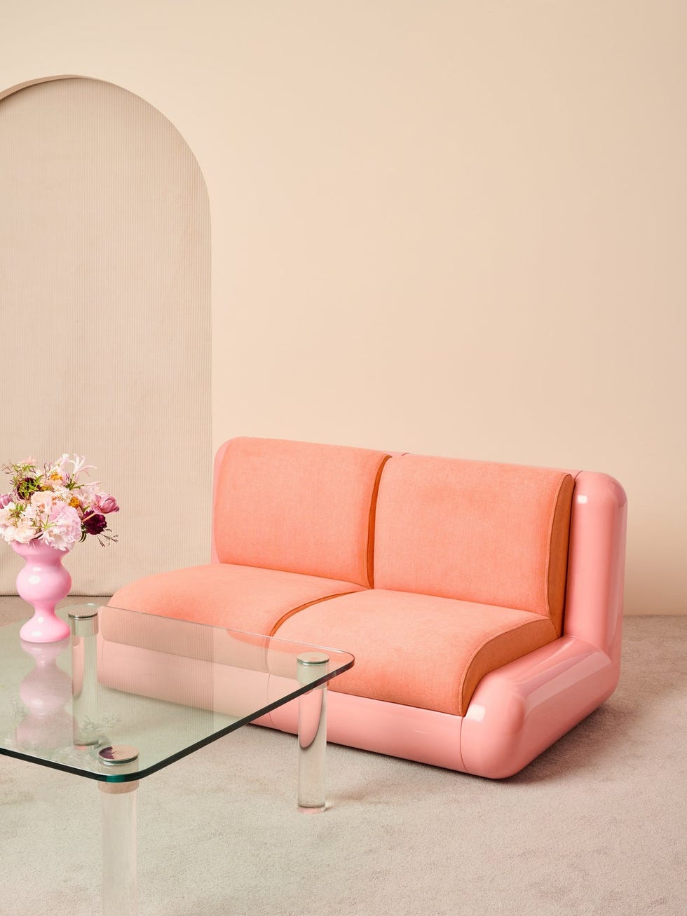 modern pink twoseater sofa with a glass coffee table and a vase of flowers