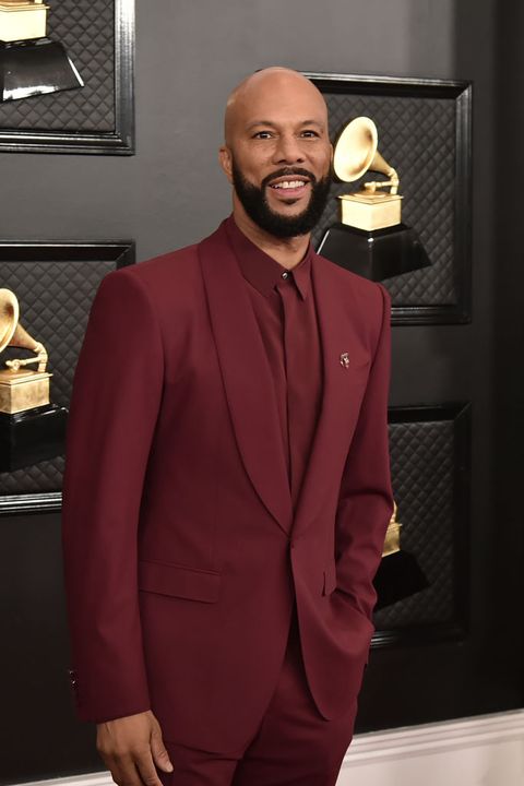 common wears a burgundy suit with a matching button up on the red carpet