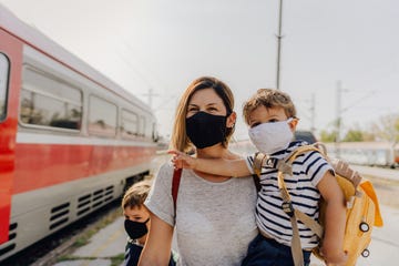 una mujer y sus dos hijos , con mascarilla, se disponen a viajar en tren