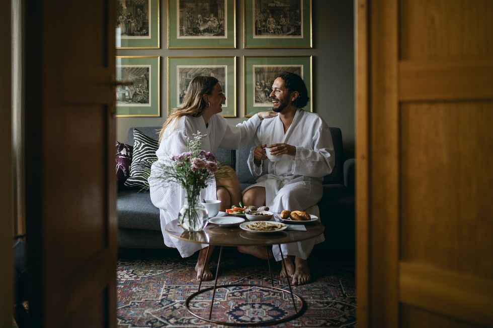 pareja sentada frente a una mesa con comida en albornoz en un hotel