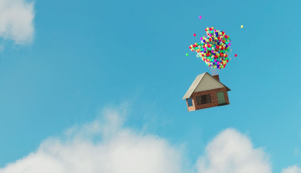 casa vuela en el cielo con globos aerostáticos de colores