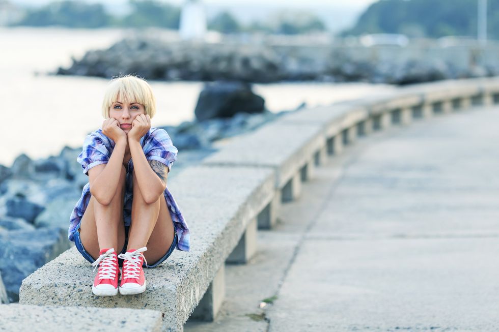 Pensive young blond woman sitting on beach