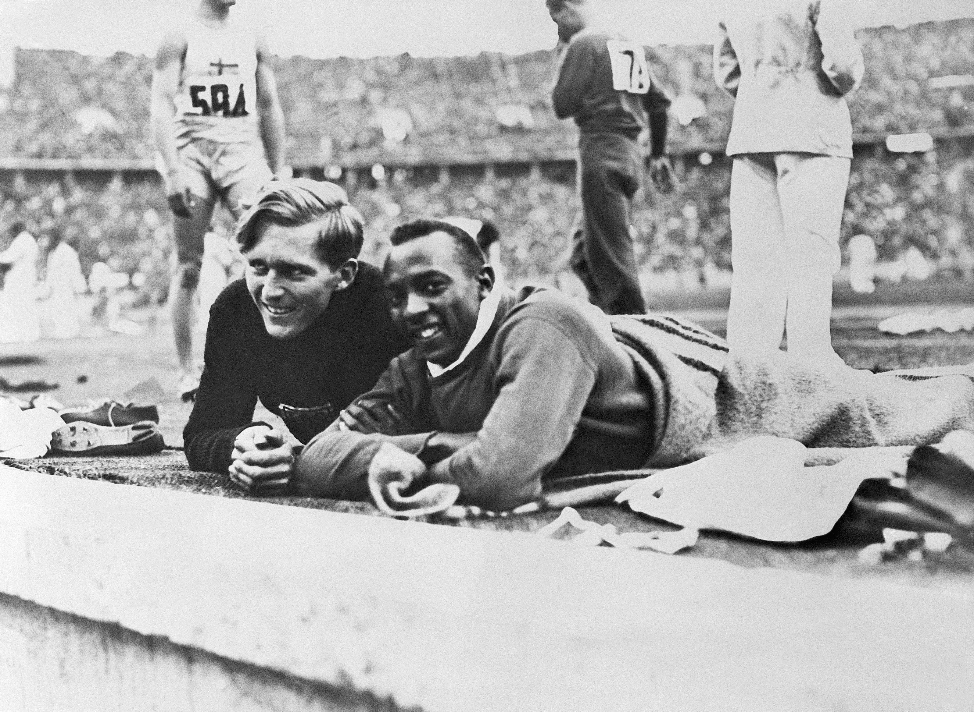 jesse owens y luz long charlan tendidos en el suelo durante la prueba de salto de longitud de los juegos olímpicos de berlín 1936