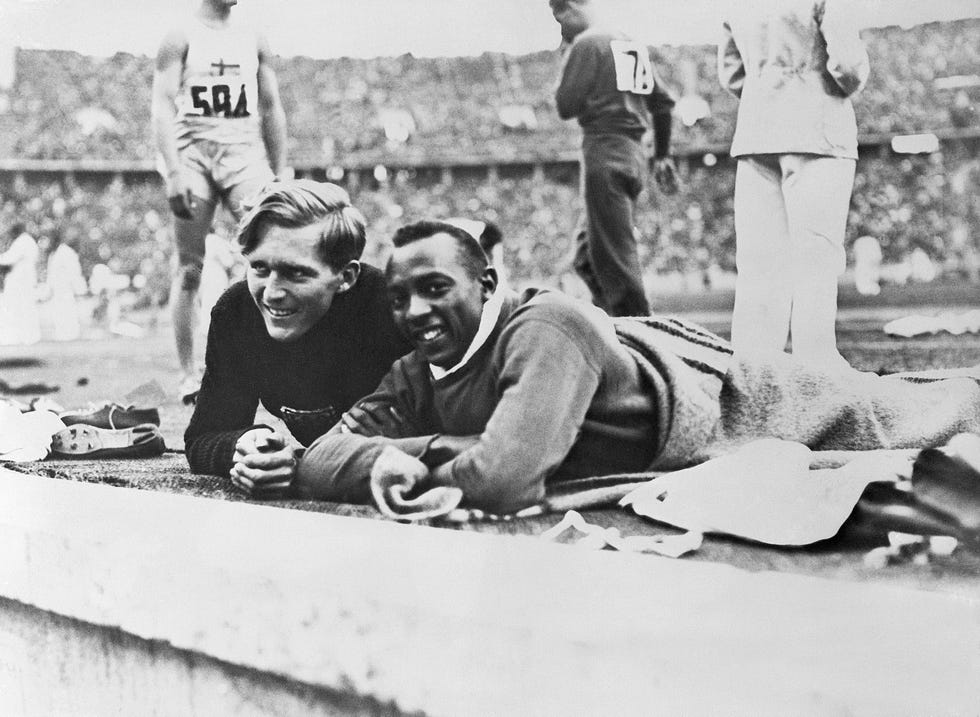 jesse owens y luz long charlan tendidos en el suelo durante la prueba de salto de longitud de los juegos olímpicos de berlín 1936