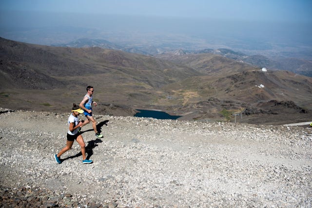 dos corredores compiten en la subida al pico veleta con sierra nevada de fondo