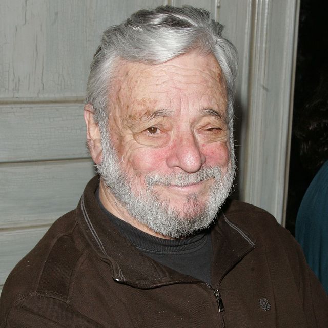 stephen sondheim smiles at the camera, he wears a brown quarter zip jacket over a dark colored tshirt
