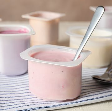 composition with plastic cups with yogurt on white table
