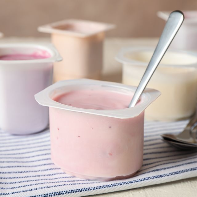 composition with plastic cups with yogurt on white table