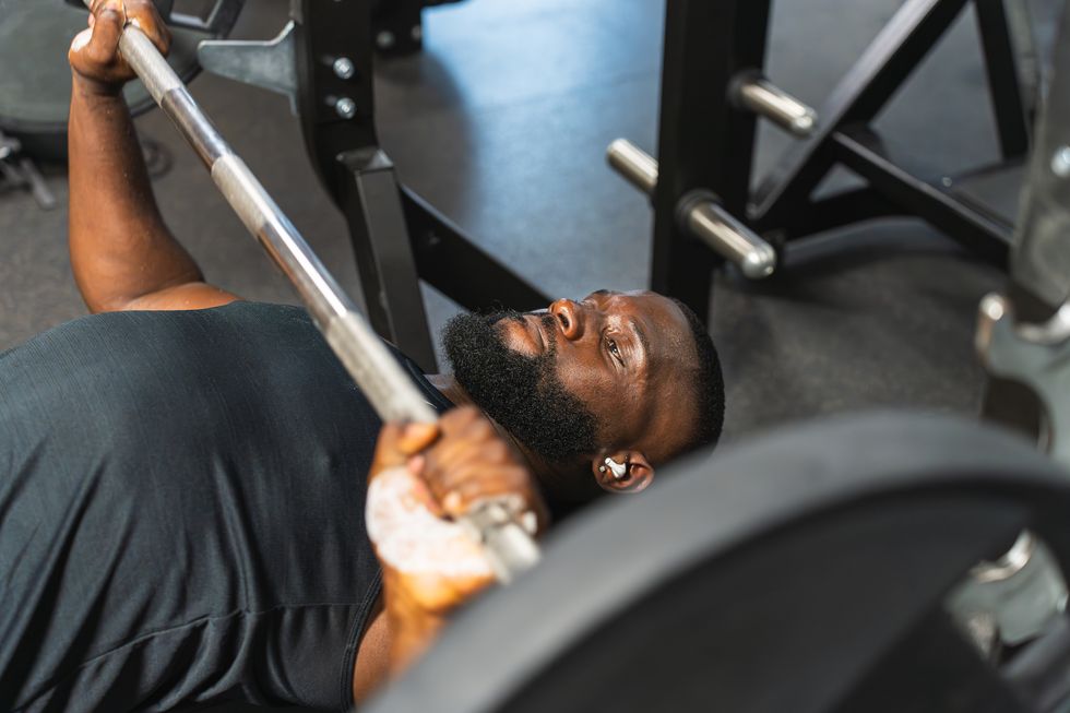 concentrated black man lifting the barbell in bench press