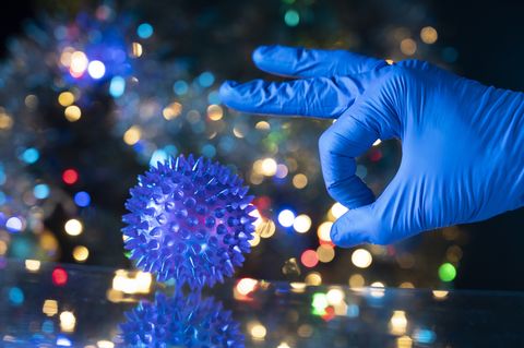 concept of elimination of the pandemic caused by the coronavirus a scientist is going to give a coronavirus strongly with his finger to eliminate it from the earth colorful christmas lights in the background interpretation with humor of the pandemic