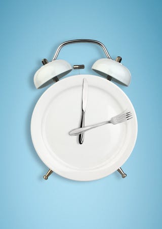 concept of intermittent fasting, diet and weight loss plate as alarm clock on blue