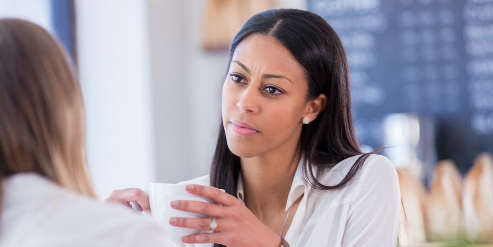 concerned young woman talks with friend in coffee shop