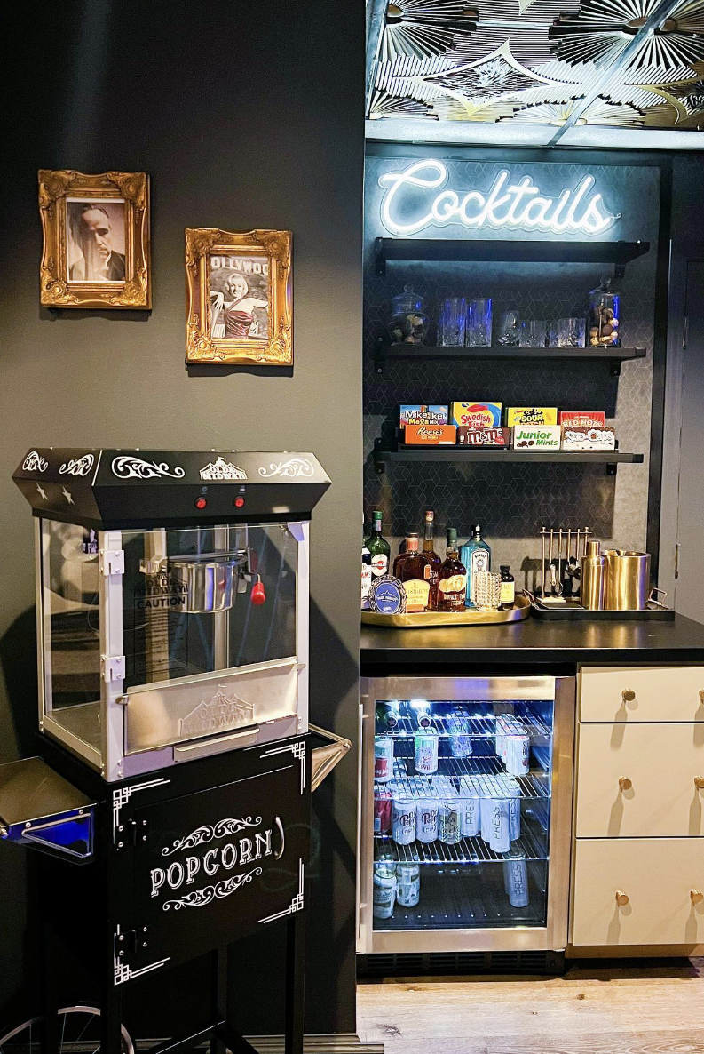 home theater concession stand with popcorn machine, mini fridge, and candy bar