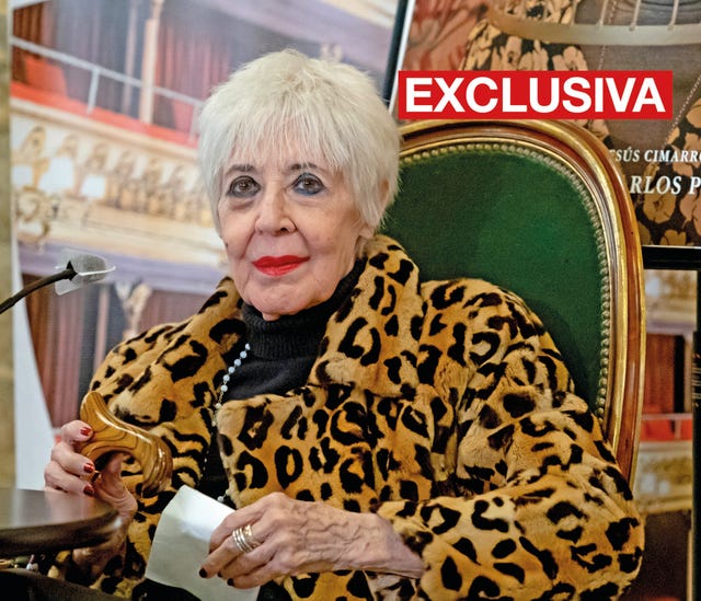 la actriz, con un abrigo de estampado felino, sentada en una butaca