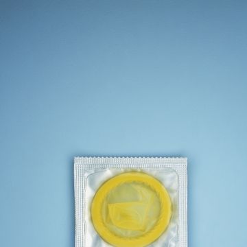 yellow condom in plastic wrapper on blue background