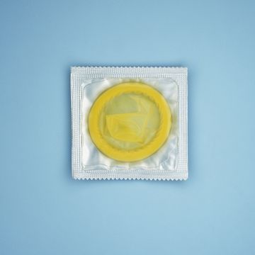 yellow condom in plastic wrapper on blue background