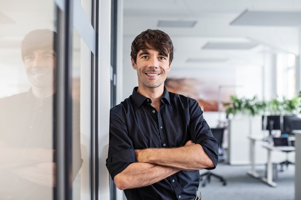 confident businessman leaning on wall in creative office
